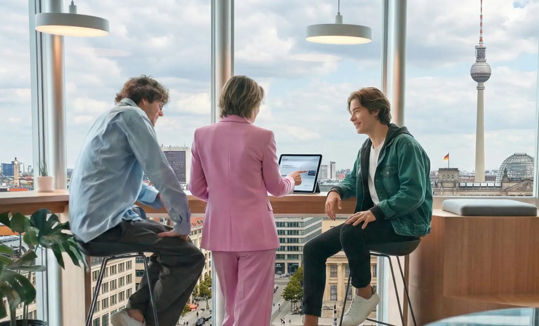 Drei Kolleginnen und Kollegen besprechen sich mit Tablet vor der Berliner Skyline