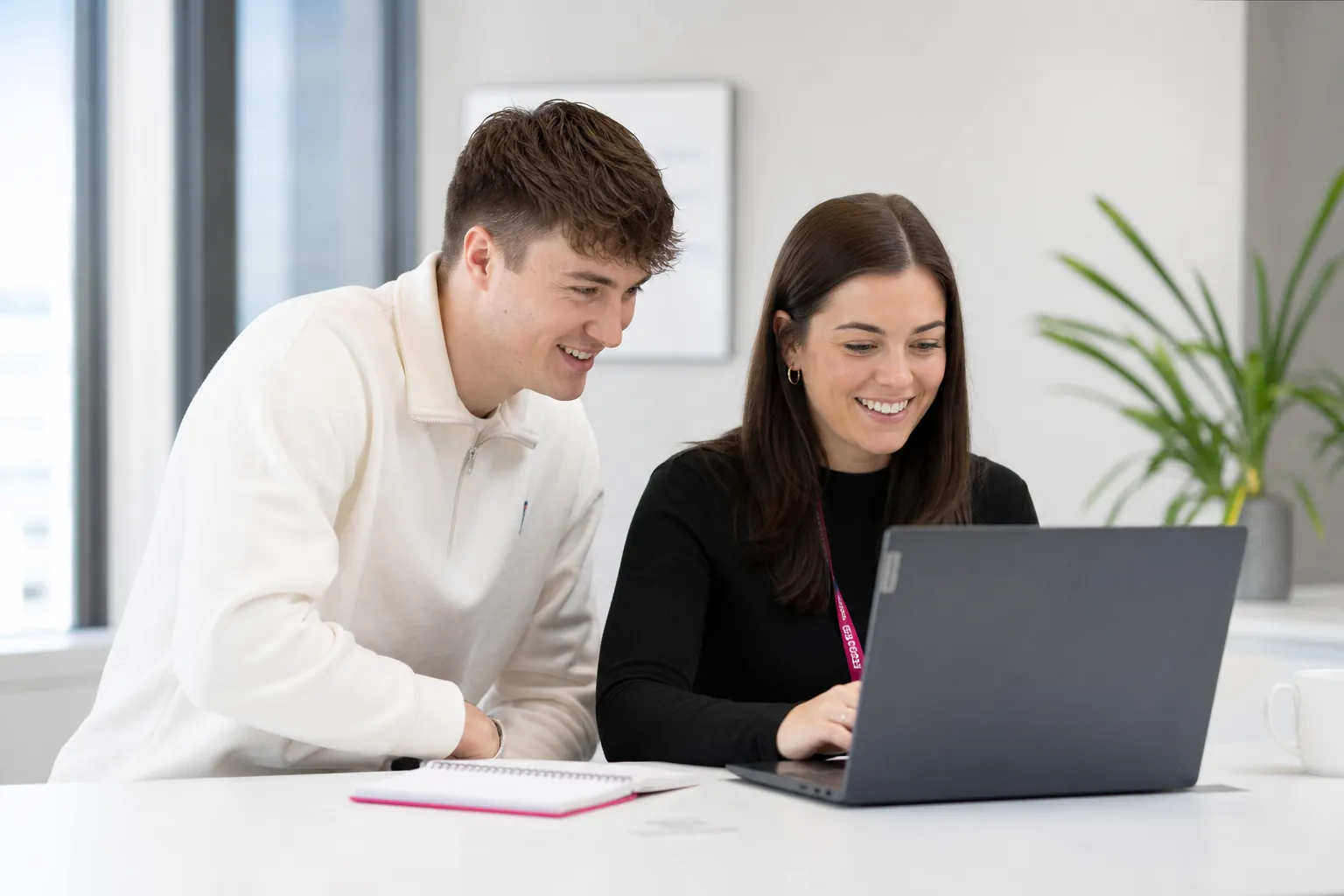 Zwei Studierende schauen gemeinsam auf einen Laptop