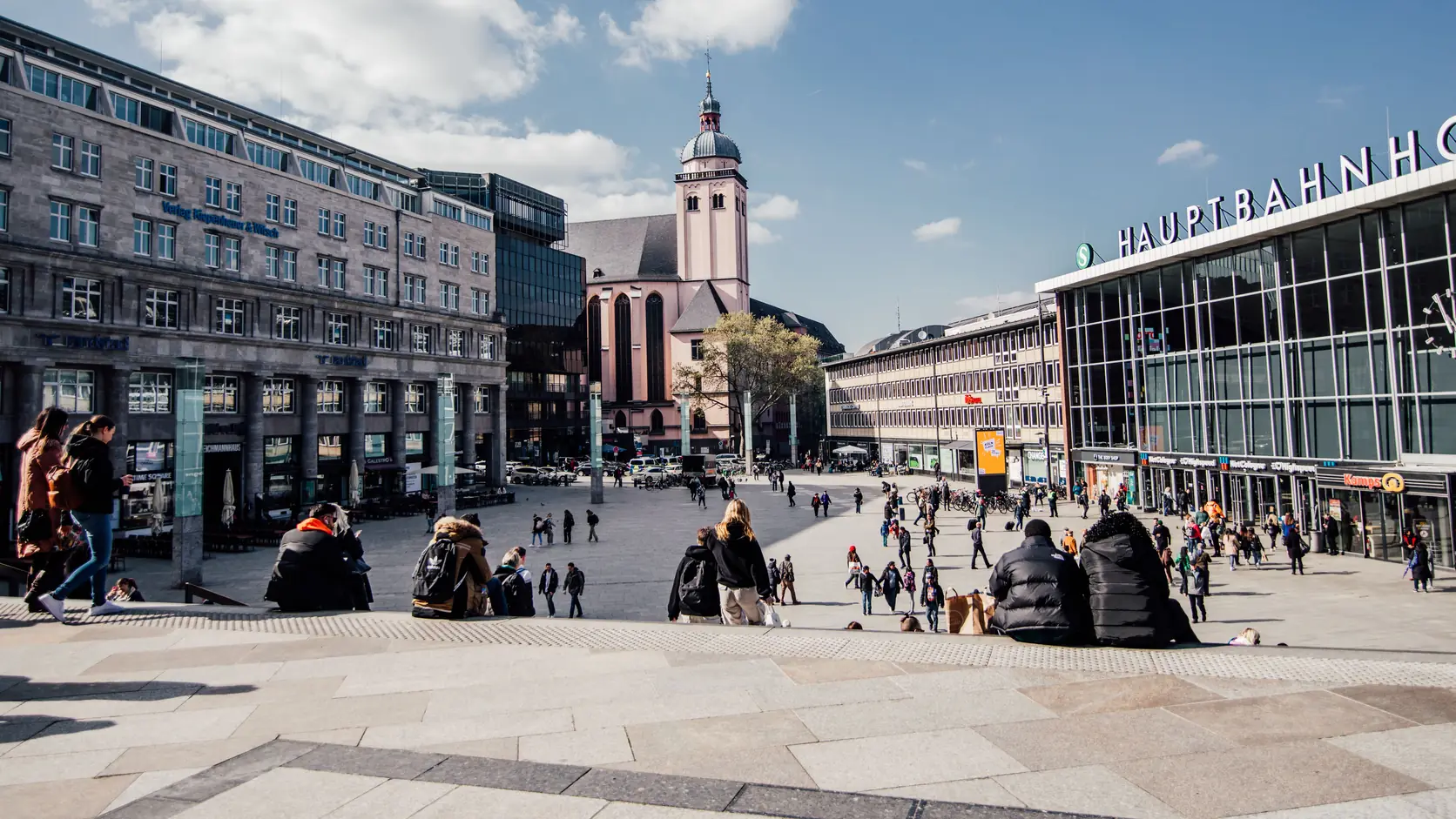 Belebter Stadtplatz mit Kirche und Passanten in einer deutschen Innenstadt