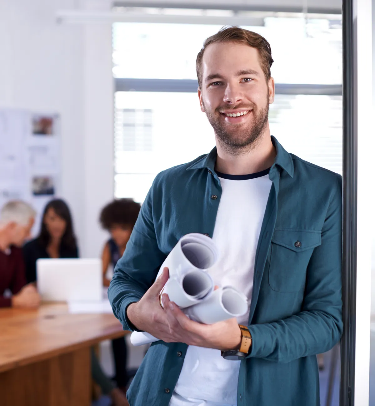 Junger Architekt mit Bauplänen im Büro